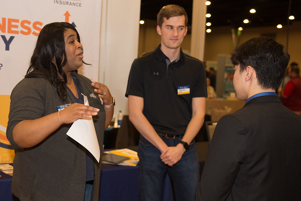 Recruiters from Liberty Mutual connect with a student at a job fair.