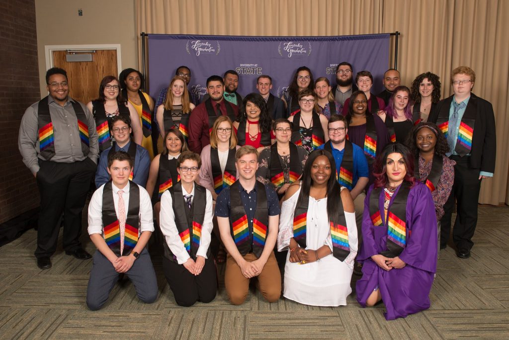 students smiling and wearing drapes with a rainbow design