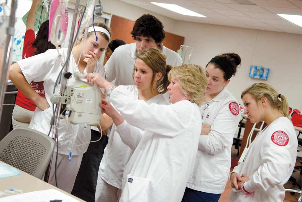 Nursing students learning how to operate a machine from a staff member.