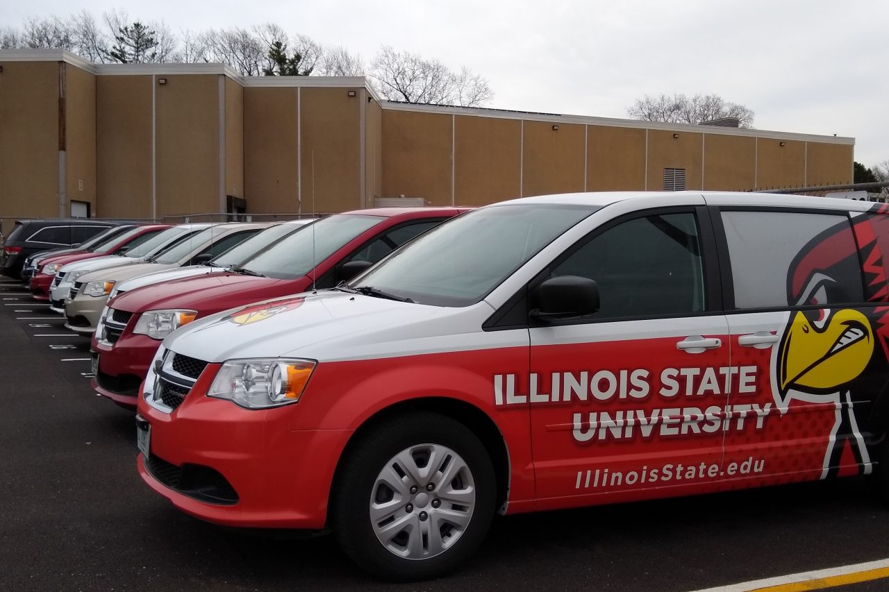 Row of University minivans parked in front of the John Green Building