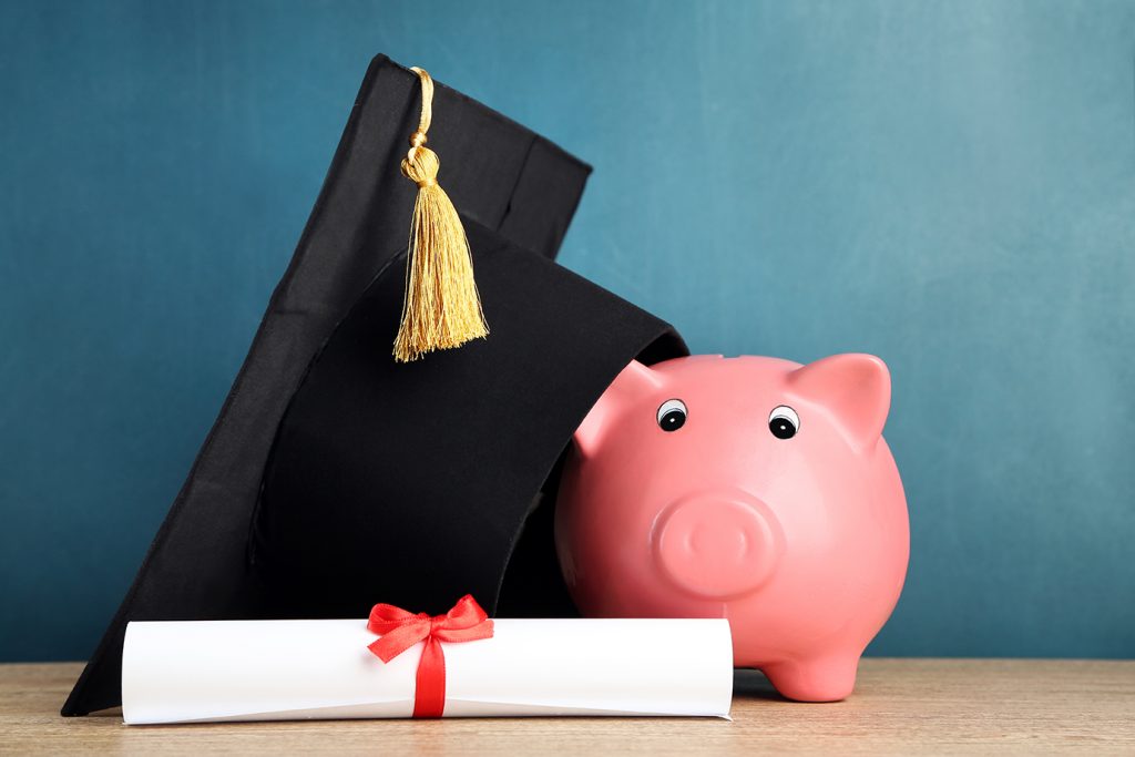 Piggy bank with grad hat and diploma on blackboard background