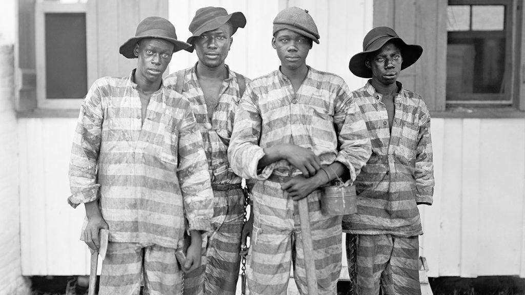 Four men standing in prison uniforms
