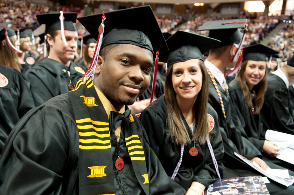 Students smile and pose in cap and gown at Illinois State graduation
