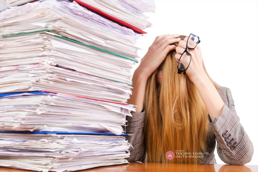 Woman with head covered next to a pile of student portfolios.