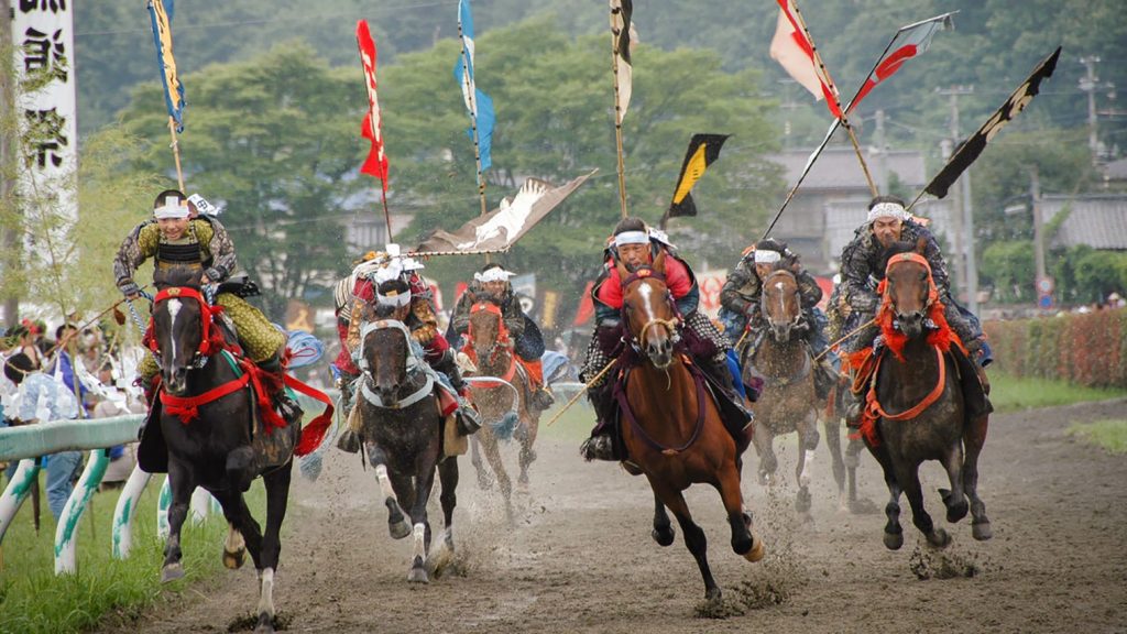 horses running on a track with people in traditional garb