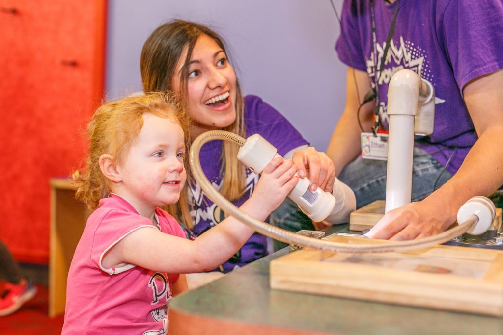 ISU Student and CDM employee Stephanie helps a guest view objects under the Microscope on a Rope in the Kid’s Medical Center Exhibit.