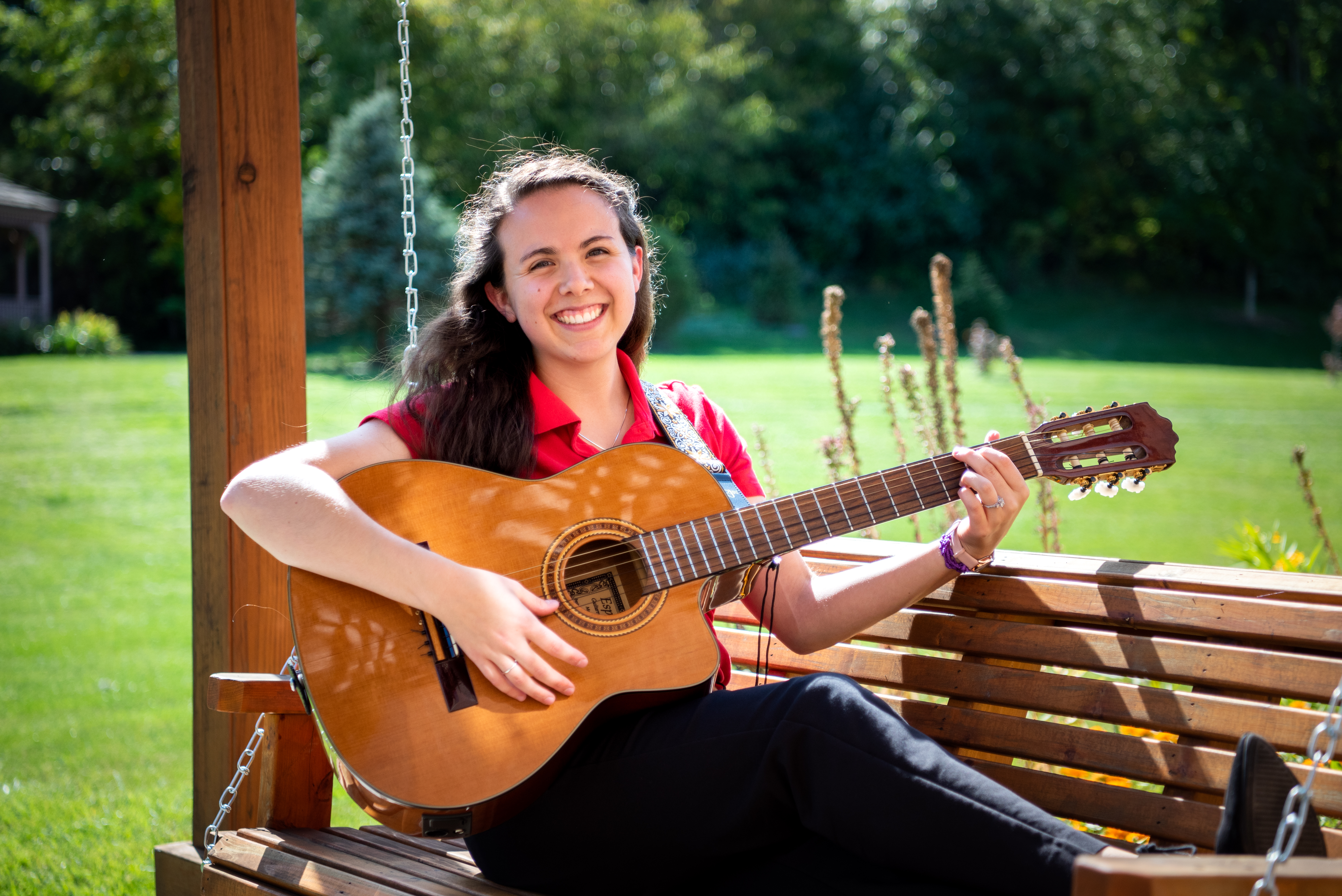 Illinois State University music therapy student Noelle Ortega playing guitar on a bench