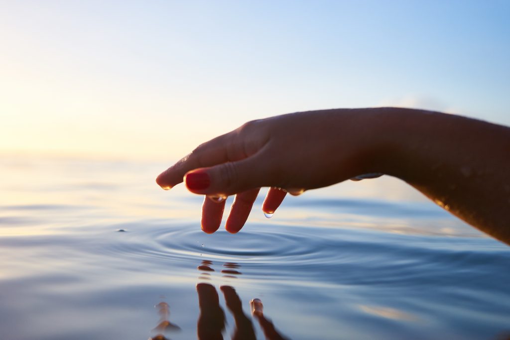 hand touching body of water