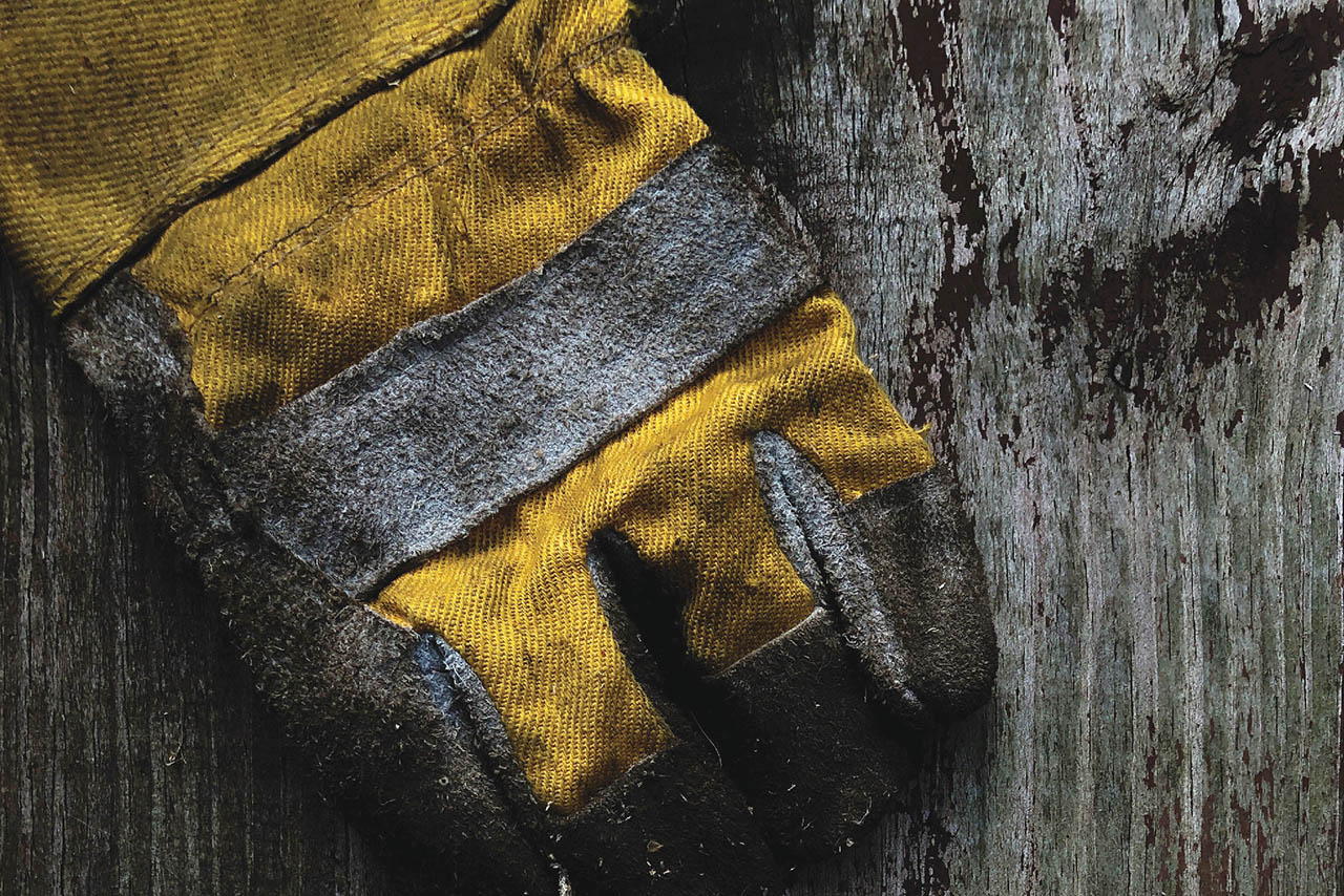 Image from production photo for Sweat/ depicting a yellow work glove on top of a wooden table.