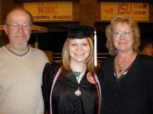 julia o'dell in her graduation cap and gown standing with her parents