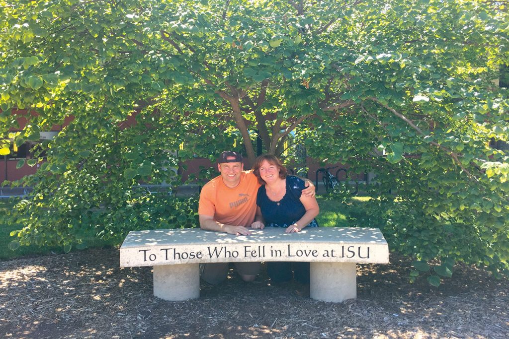 Couple sitting in front of bench that reads "To those who fell in love at ISU"