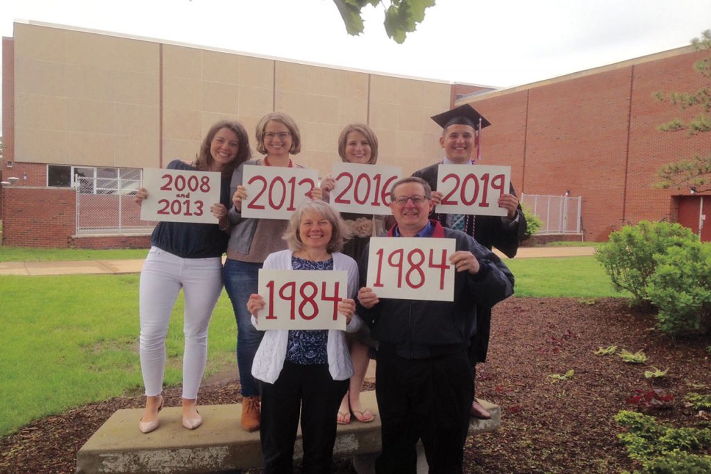Family of six holding up signs of the years they graduated.