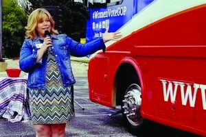 Woman with microphone standing in front of bus