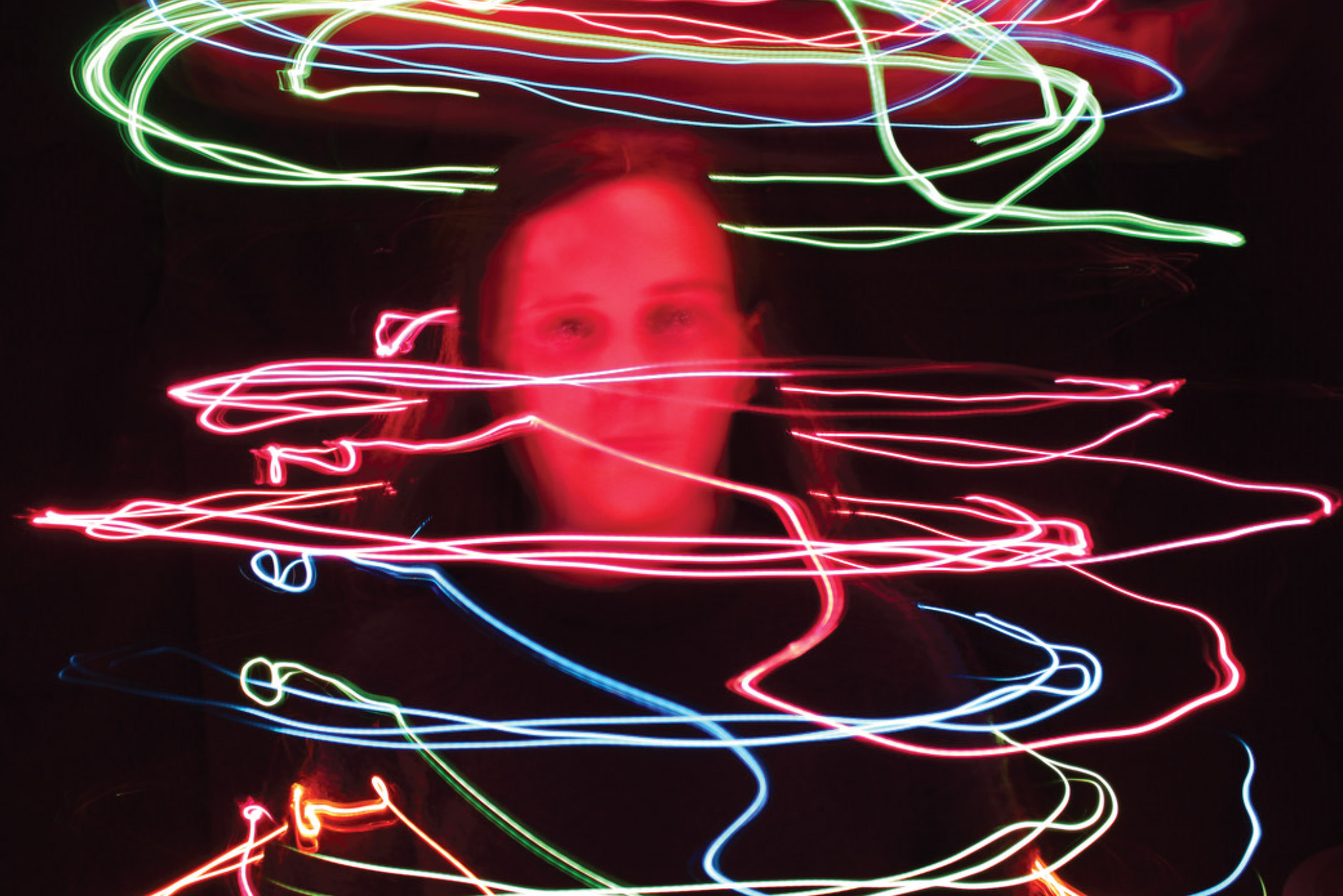 Digital Photograph "Energy" depicting a black background with a person surrounded by multi-colored neon squiggly lights.