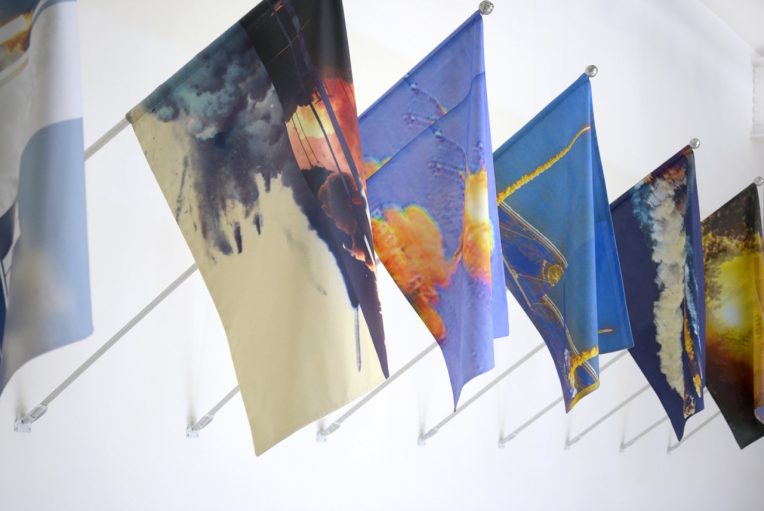Kambui Olujimi, T-Minus Ø, 2017. Installation of 13 mounted flags. Digital print on cotton with aluminum pole, artist-made finial, zinc pole mount. Courtesy of the artist.