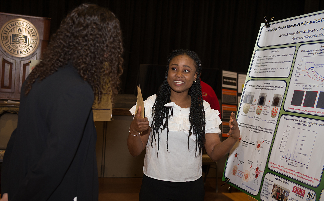 Woman talking to another person in front of a research poster