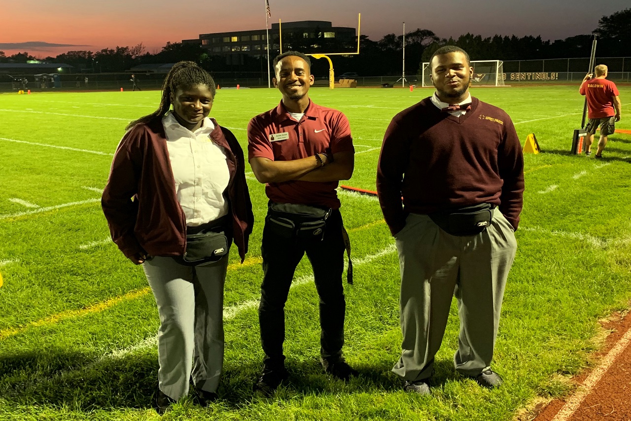 Three people standing on football field