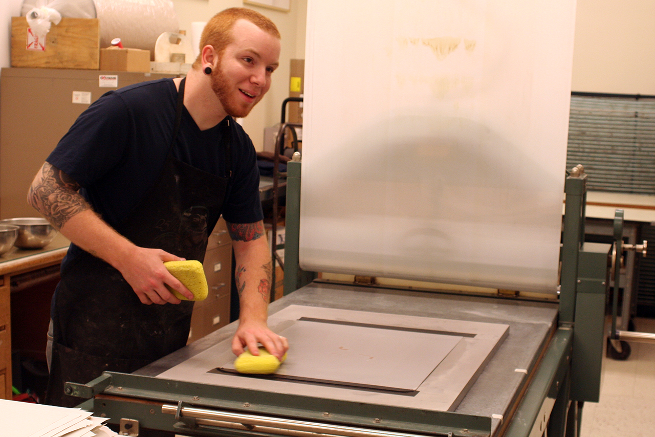 Student sponging a lithography plate