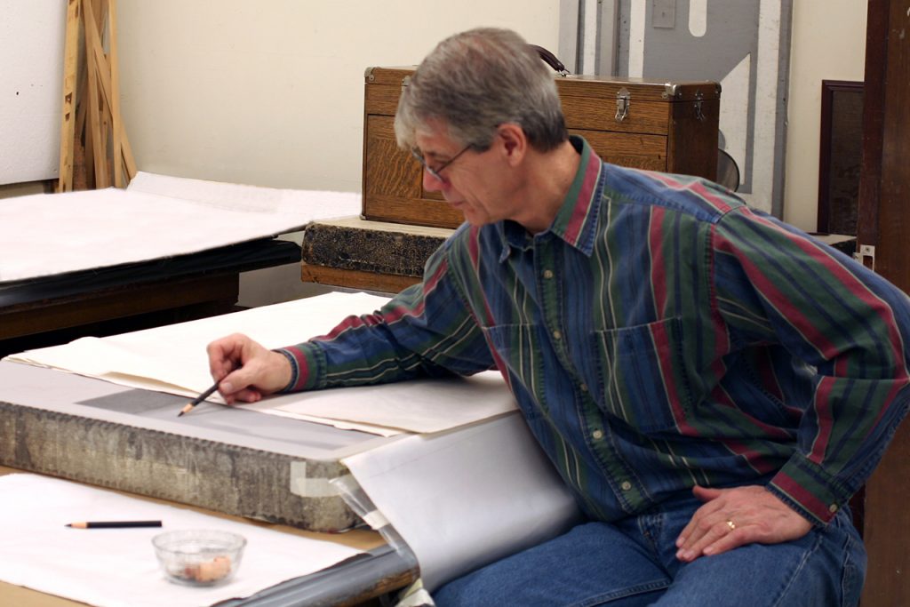 artist drawing on a lithography stone