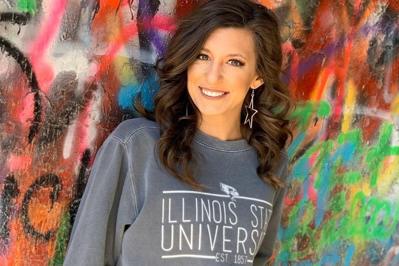 Student against a colorful wall wearing an ISU sweater