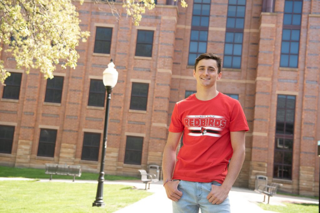 Young man standing in front of college building
