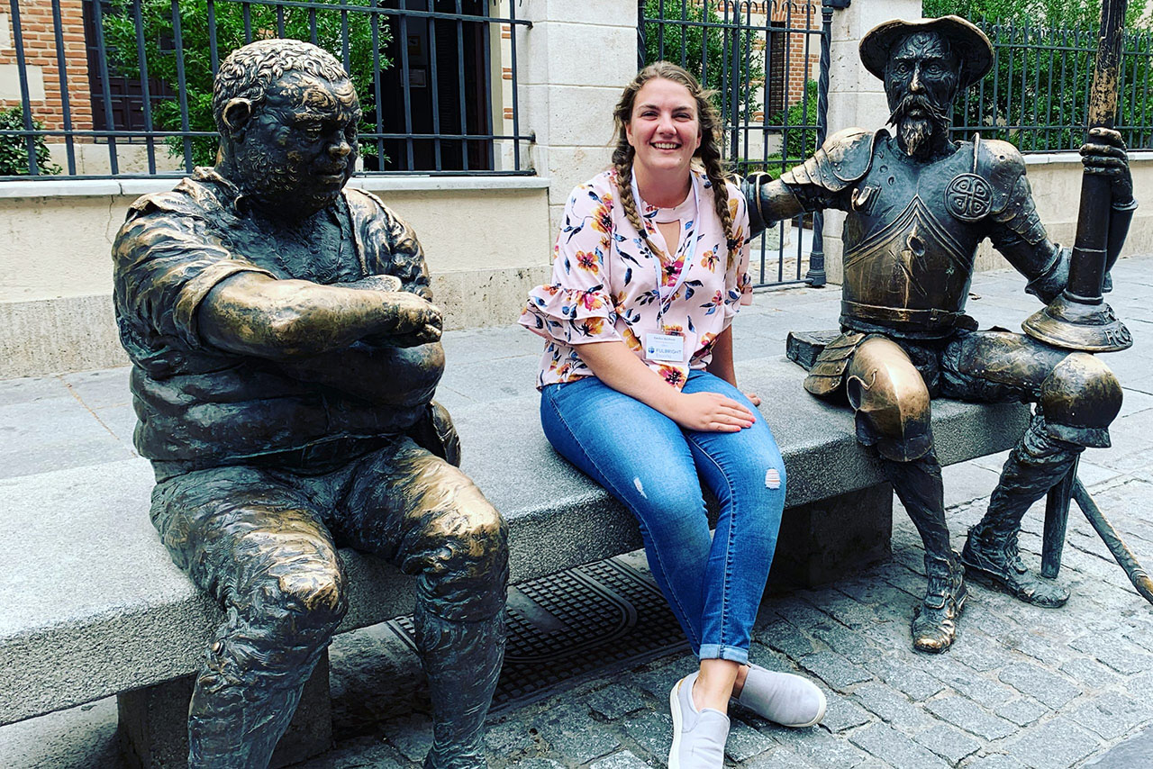 Emilee Baldwin '19 sits with statues of Don Quixote and Sancho Panza before her Fulbright orientation in Spain.