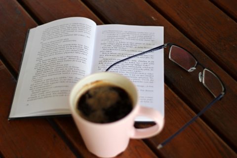 coffee, open book, and glasses on a wooden table