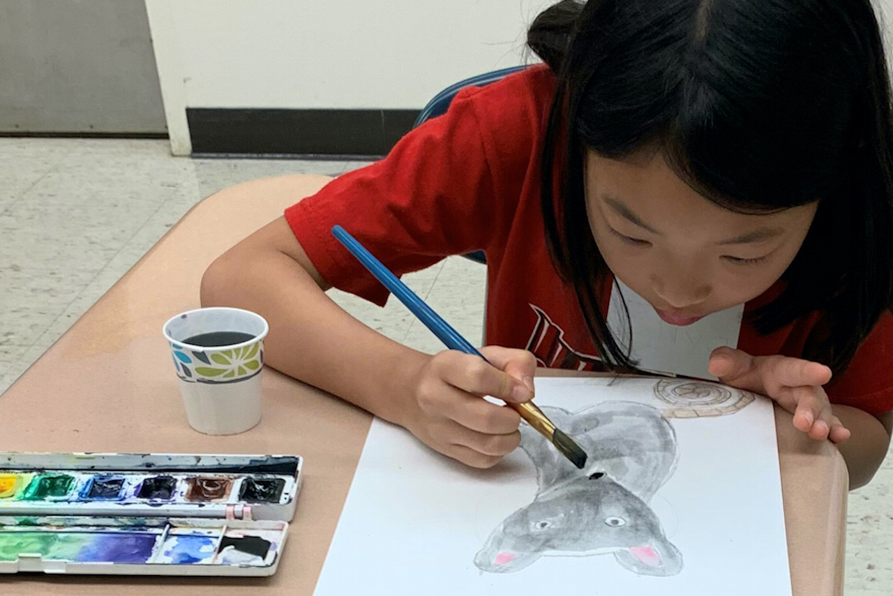 Girl painting a mouse during a Saturday visual arts class
