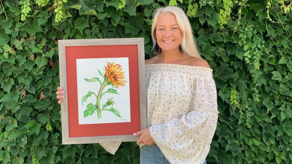 woman holding a painting of a sunflower
