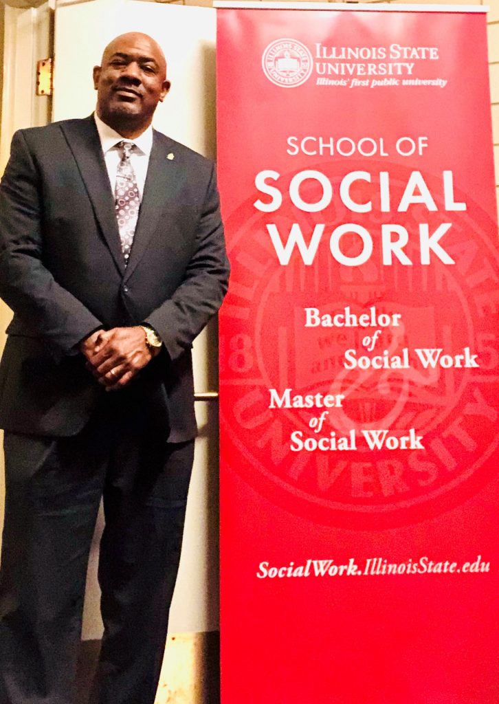 Nathan Stepehsn standing next to a banner that reads School of Social Work
