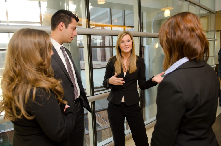 People in business attire standing, laughing, and talking