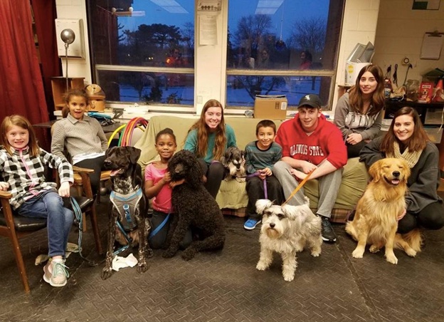 College mentors and elementary school mentees pose with four dogs