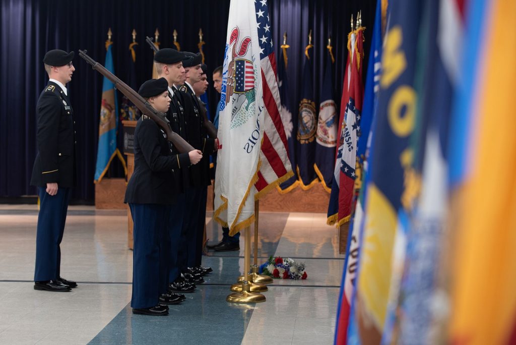 Military members stand guard at a set of flags