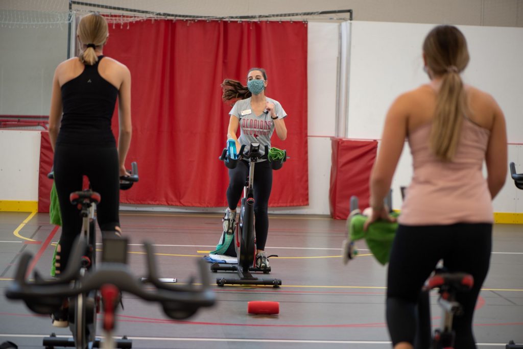 Woman teaches a cycling course as two female riders look on 
