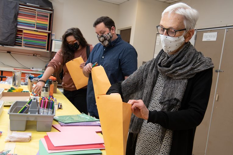 From right to left, Judith Briggs, AJ Kepa, and Katie Barko stuff packets with art supplies for the Saturday kids' art classes.
