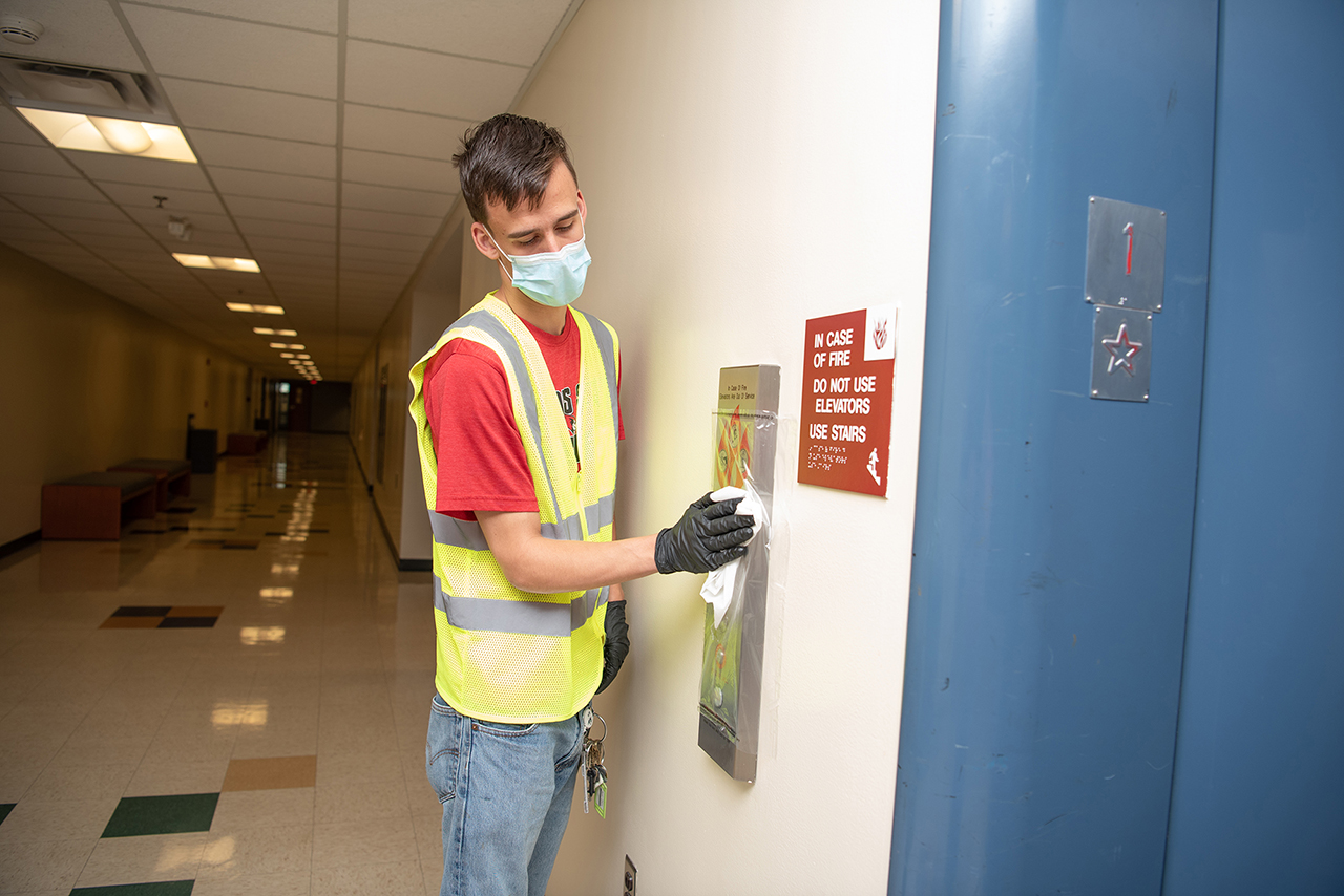 A BSW sanitizes an elevator call box.