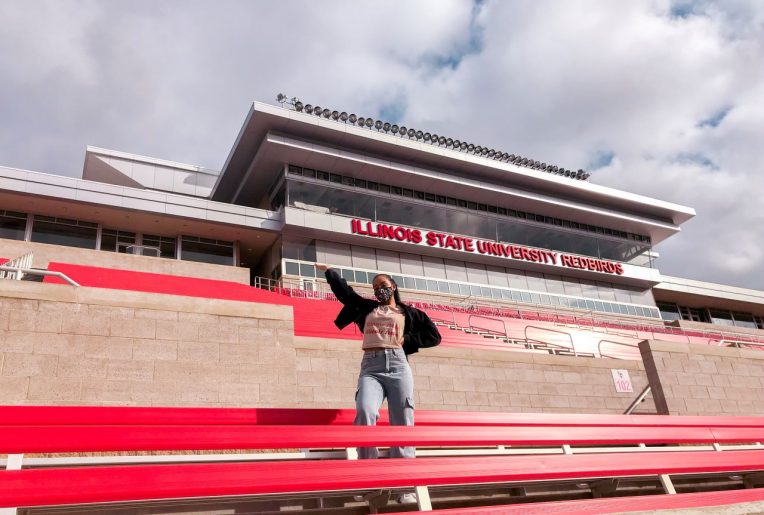 Redbird Rep student influencer poses in the stands at Hancock Stadium