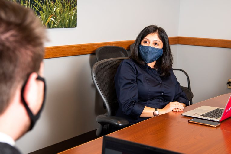 Woman in a mask during an interview with another individual