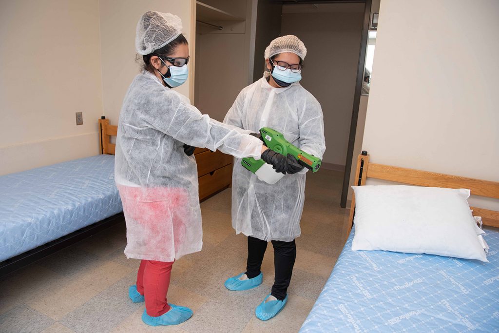 Two BSWs sanitize a room.