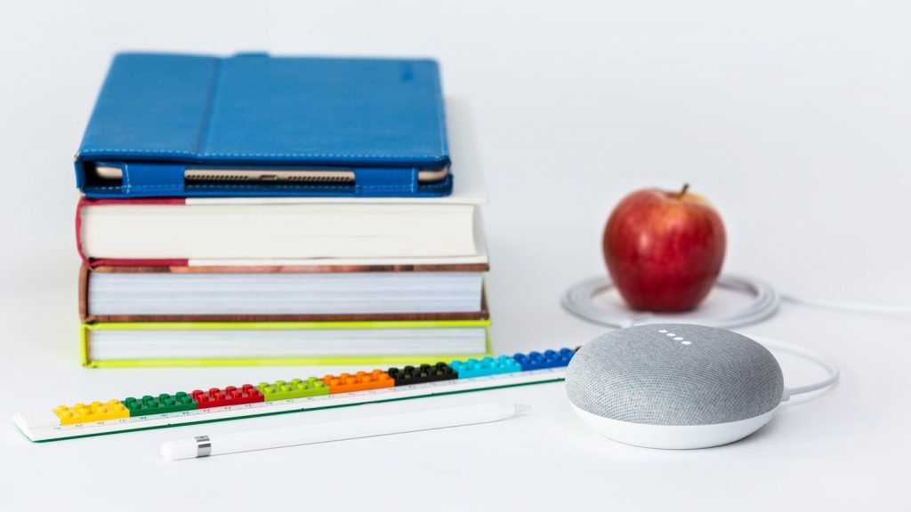 A stack of book with an apple and speaker