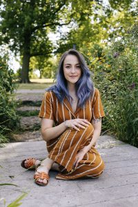 Woman with purple hair sitting outside in a park