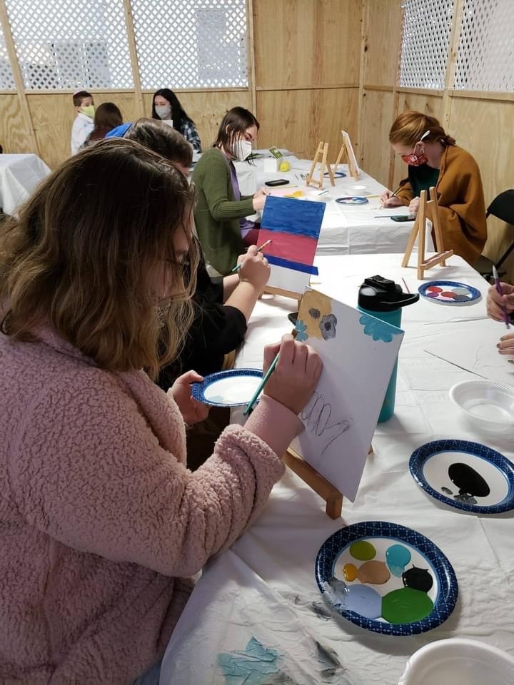 Members of the Jewish group Chabad paint canvases while socially distanced and wearing masks. 