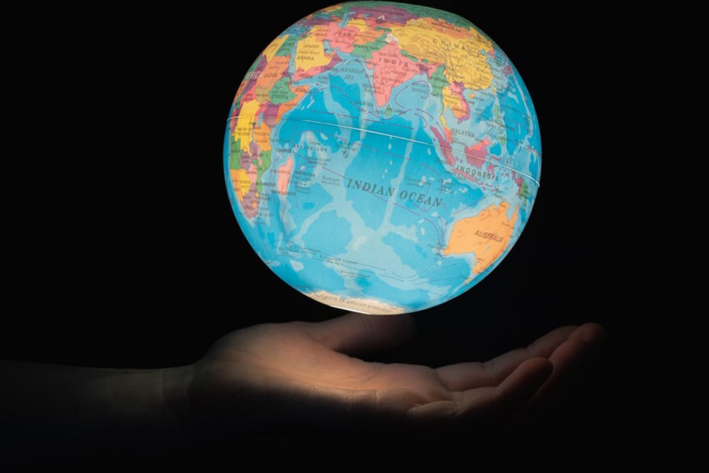 A photo of a hand under a lit up globe