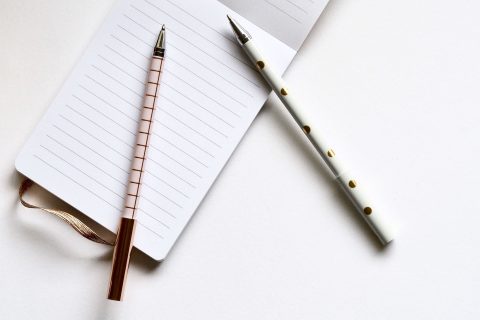 Two pens on notebook and a table