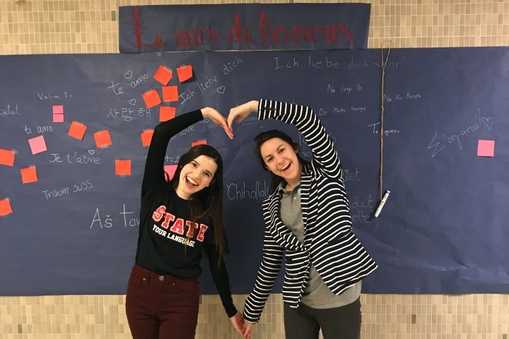 Two people making a heart out of their arms
