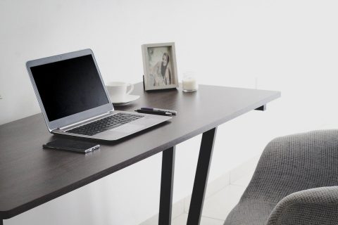 lap top on a wood desk next to a chair