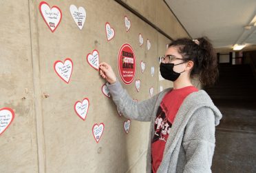 Student reading a heart shaped message on a wall