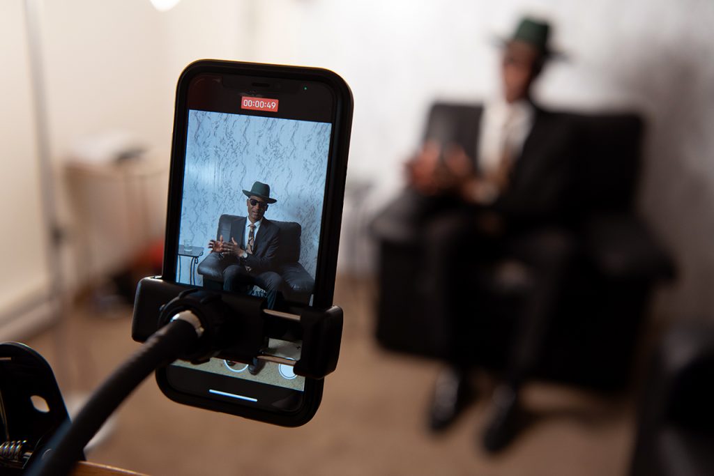 Phone, in focus, recording a man talking in a leather chair