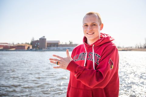 Cody Rogers standing in front of Lake Bloomington, wearing one of the rings that his company produces