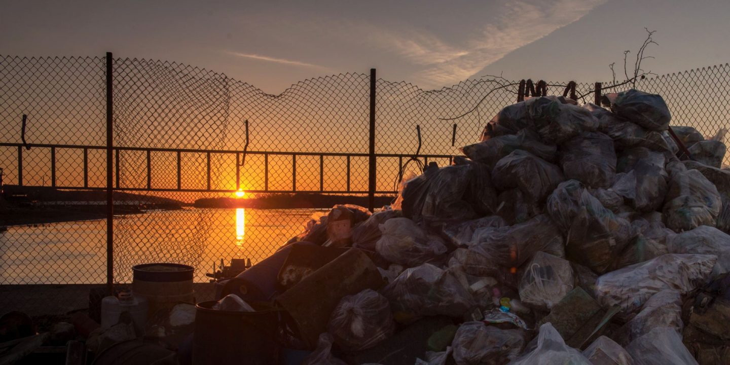 Redbird Impact cover Fall 2018 no text image of Mississippi River with a bridge in the background and a pile of trash in the foreground